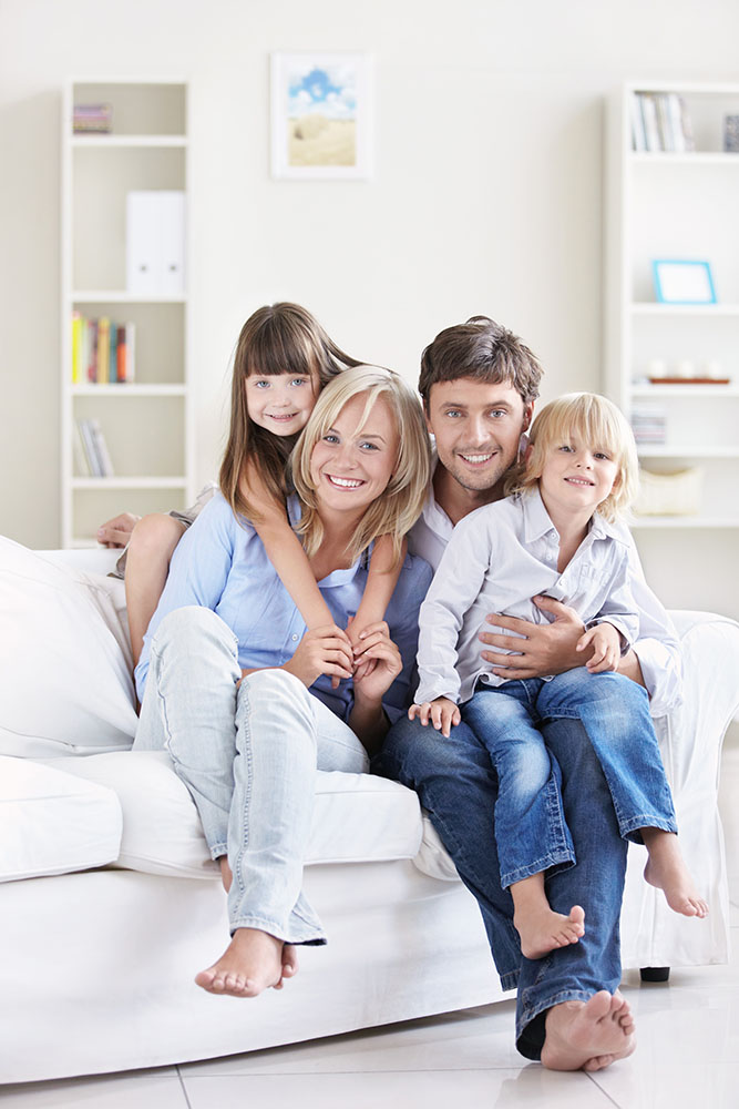 Family sitting happily on white sofa